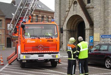 Brandweer hangt spandoek "Dorp in de Kijker" aan kerktoren